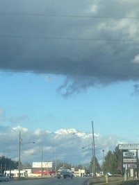 a cloudy sky over a street with cars on it